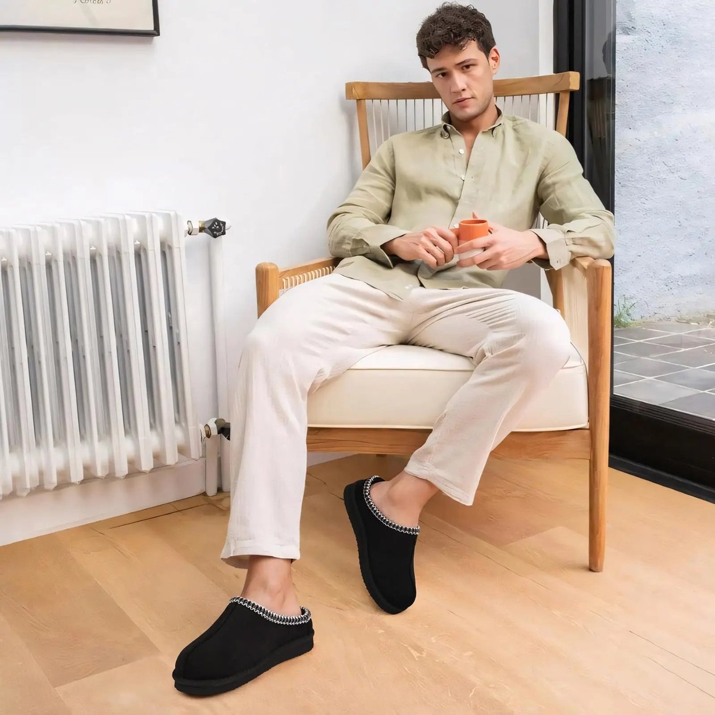 Mann i stol med svarte Cozy Slipper på føttene